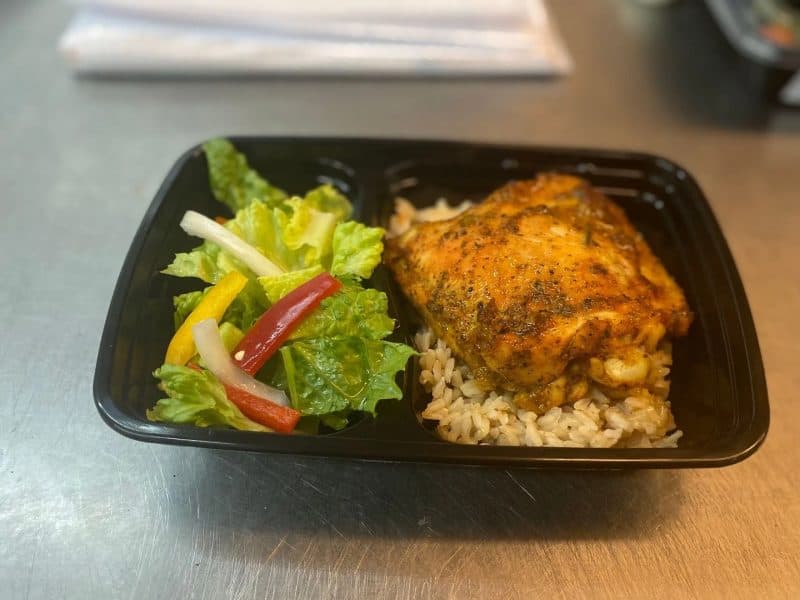 Prepared meal with seasoned chicken, rice, and salad